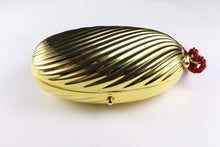 Golden oval-shaped clutch with tassel