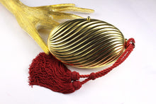 Golden oval-shaped clutch with tassel